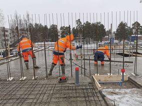 Työmiehiä tasoittamassa betonilattiaa